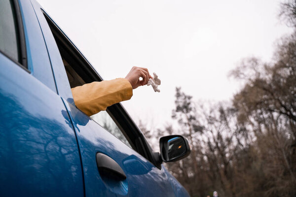 cropped view of man throwing away used napkin from car