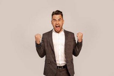 excited man shouting while showing yeah gesture isolated on grey