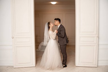 full length view of young newlyweds holding hands near entrance to bedroom