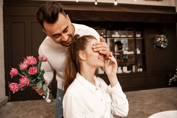 Young Man Bouquet Tulips Covering Eyes Smiling Woman Cafe — Foto de Stock