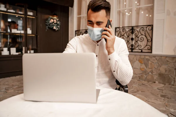 Young Man Medical Mask Working Laptop While Talking Smartphone Cafe — 스톡 사진
