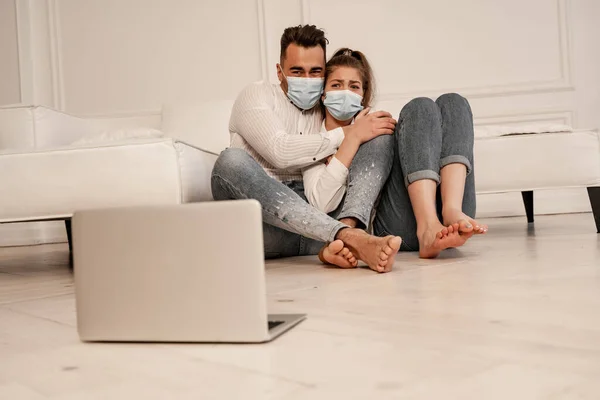 Scared Couple Medical Masks Watching Horror Film Laptop Floor — Φωτογραφία Αρχείου