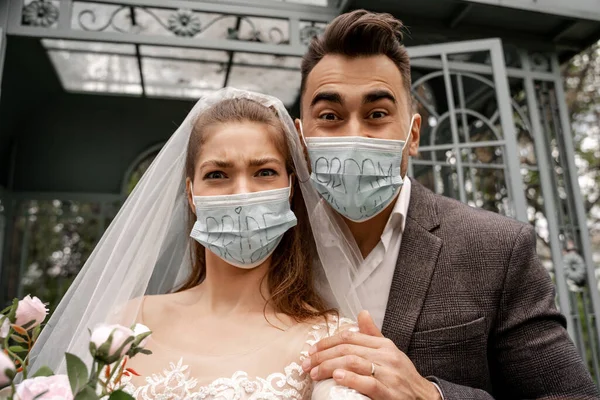 Excited Newlyweds Safety Masks Bride Groom Lettering Looking Camera Park — Fotografia de Stock