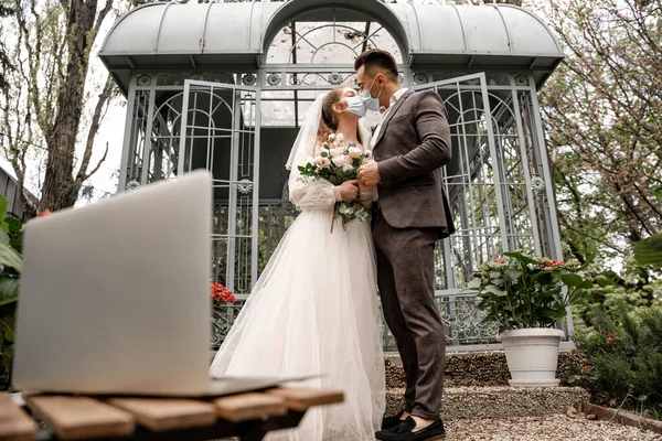 Young Newlyweds Medical Masks Kissing Outdoors Laptop Blurred Foreground — Fotografia de Stock