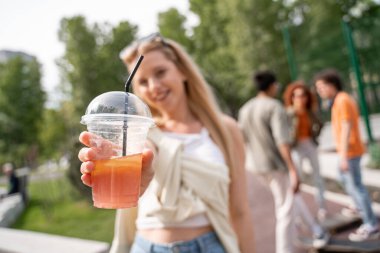 Bulanık kadının elindeki taze kokteylin seçici odağı