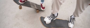 partial view of men in sneakers riding skateboards outdoors, banner clipart