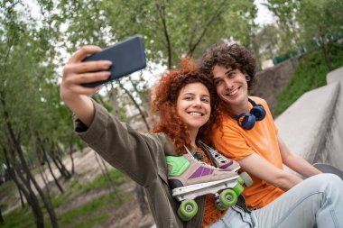 Patenli mutlu kadın parkta kıvırcık arkadaşıyla selfie çekiyor.