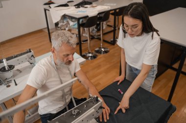 Atölyede kumaşla çalışan çok ırklı terzi ve terziye yüksek açılı bakış açısı 