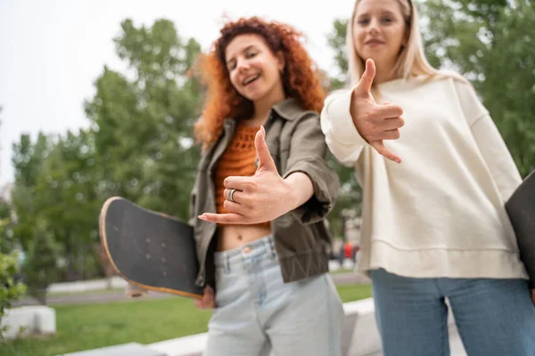 Verschwommene Skater Zeigen Hängende Geste Während Sie Die Kamera Lächeln — Stockfoto