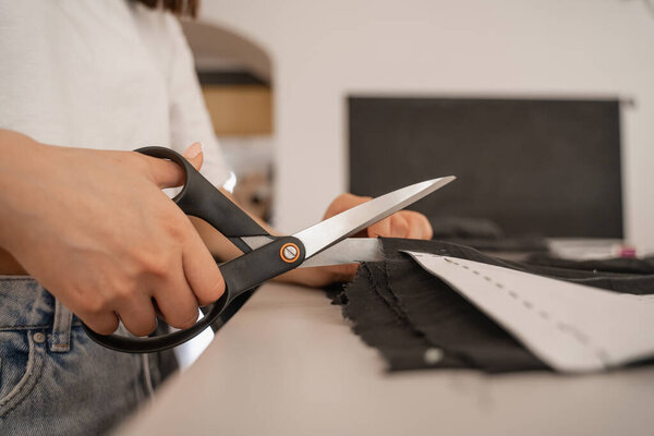 Cropped view of designer cutting cloth with sewing pattern 