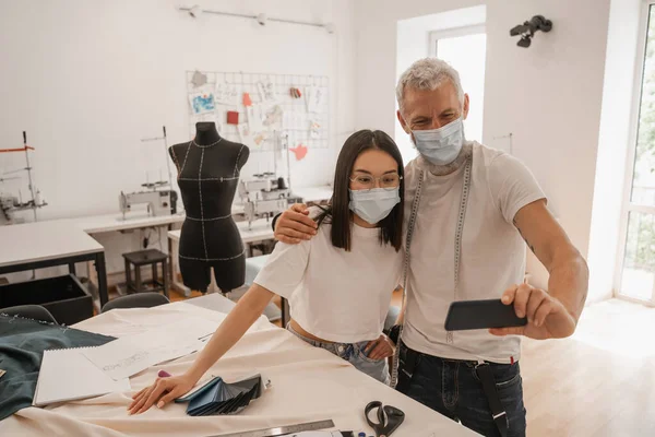 Diseñadores Interraciales Máscaras Médicas Tomando Selfie Smartphone Atelier —  Fotos de Stock