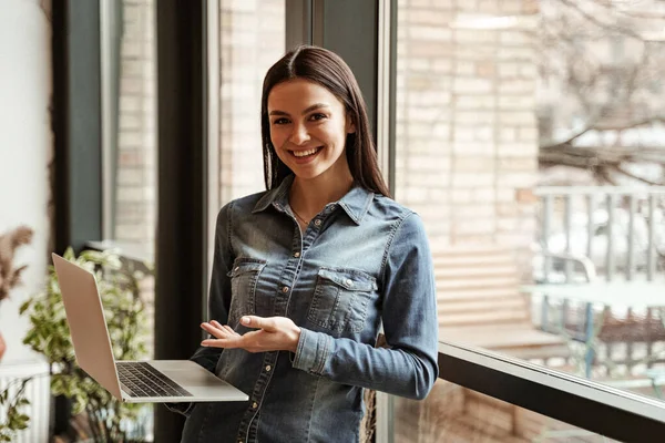 Young happy freelancer pointing with hand at laptop — Stock Photo