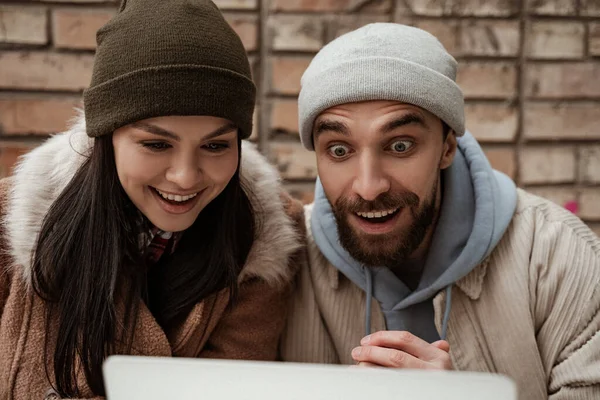 Amazed couple in beanie hats and jackets outside — Stock Photo