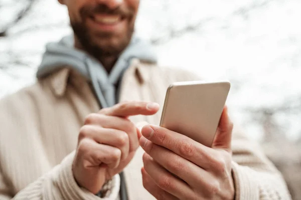 Cropped view of bearded man pointing with finger at smartphone — Stock Photo