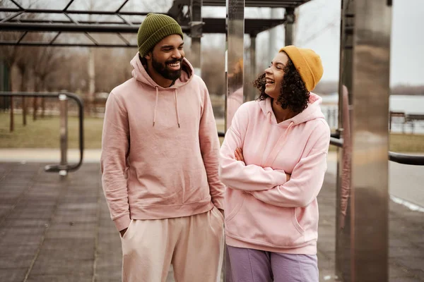 Cheerful african american couple in sportswear looking at each other while talking outdoors — Stock Photo