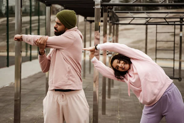 Young african american couple in sportswear warming up outdoors — Stock Photo