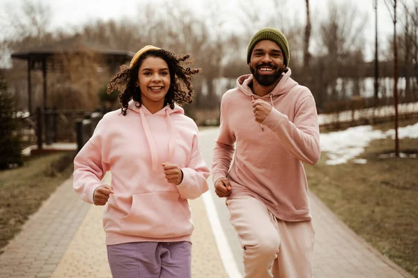 Cheerful african american joggers looking at camera while running outdoors — Stock Photo