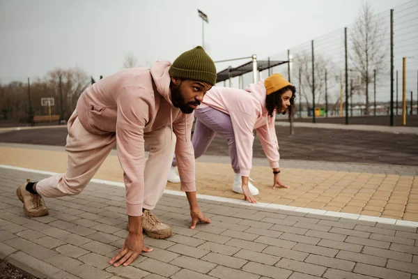 Jeunes coureurs afro-américains debout en position de départ bas sur un terrain de sport — Photo de stock