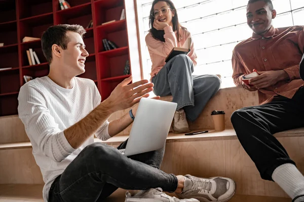 Feliz interracial estudiantes sonriendo mientras sentado en escaleras, senior 2021 - foto de stock