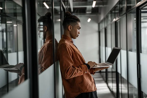 Vue latérale de l'étudiant afro-américain en utilisant un ordinateur portable dans le hall — Photo de stock