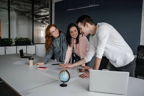 Allegri giovani studenti sorridenti mentre guardano compagno di classe che indica carta con progetto — Foto stock