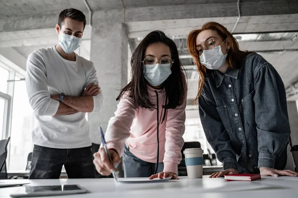 Молодые студенты в медицинских масках, работающие над проектом — стоковое фото