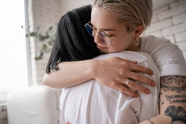 Tattooed woman in glasses hugging brunette girlfriend — Stock Photo