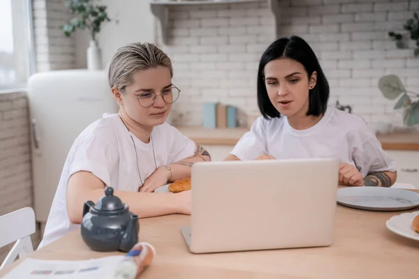 Tatuado lésbicas casal olhando para laptop no cozinha — Fotografia de Stock