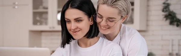 Alegre pareja lesbiana sonriendo en casa, pancarta - foto de stock