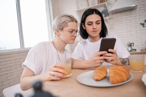 Morena mujer usando smartphone cerca de novia en cocina - foto de stock