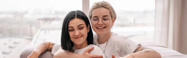 Jeune couple lesbien souriant tout en refroidissant à la maison, bannière — Photo de stock