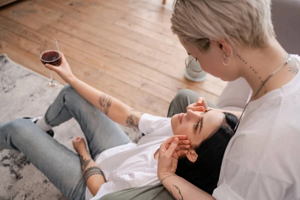 Femme tatouée floue regardant petite amie avec un verre de vin rouge — Photo de stock