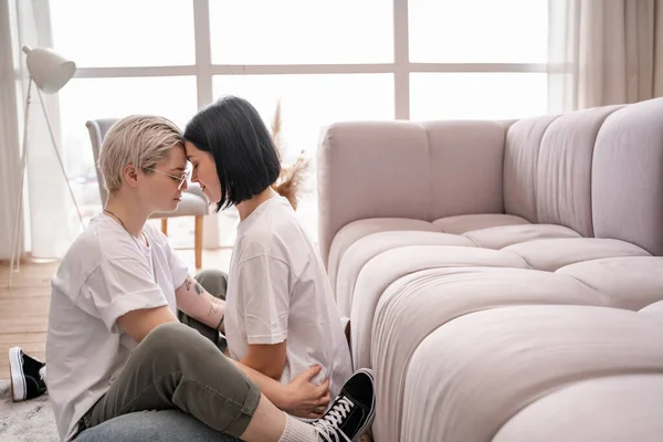 Side view of cheerful lesbian couple with closed eyes in living room — Stock Photo