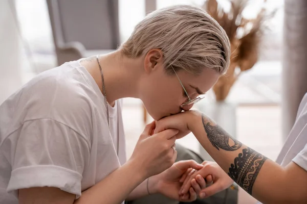 Joven lesbiana besos mano de tatuado novia - foto de stock