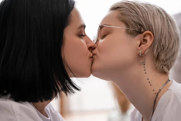 Vista lateral de amante lesbiana pareja besándose en casa - foto de stock
