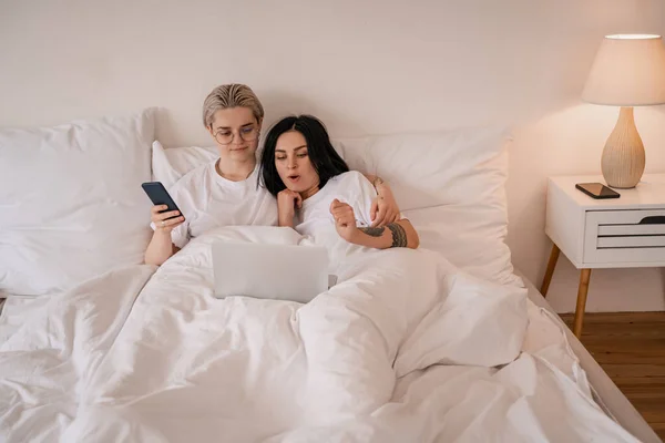 Junges lesbisches Paar liegt im Bett und schaut sich Film auf Laptop an — Stock Photo