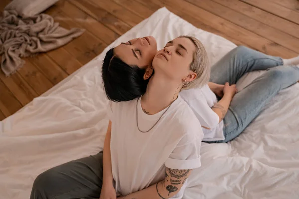Alto ángulo vista de lesbianas pareja sentado espalda con espalda en la cama - foto de stock