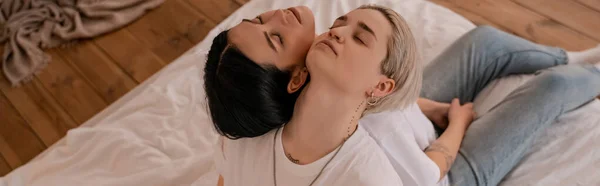 High angle view of lesbian couple sitting back to back on bed, banner — Stock Photo