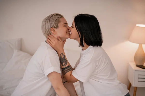 Seitenansicht eines glücklichen lesbischen Paares, das sich im Schlafzimmer küsst — Stockfoto
