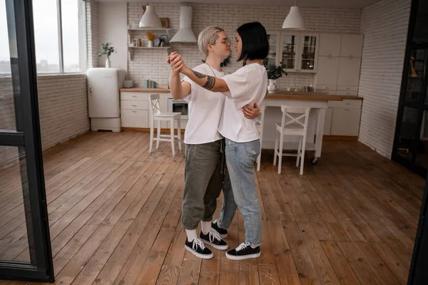 Larga duración de pareja de lesbianas cogidas de la mano y bailando en la cocina - foto de stock