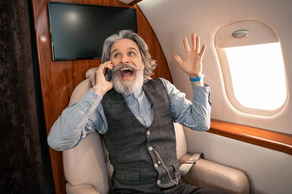 Excited businessman talking on cellphone in private airplane — Stock Photo