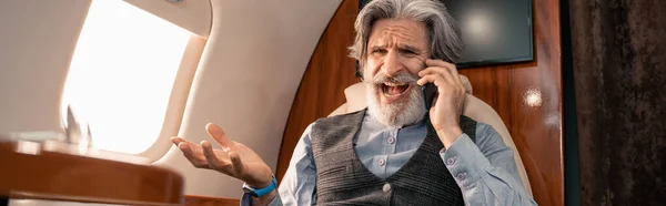 Positive businessman talking on mobile phone in private jet, banner — Stock Photo