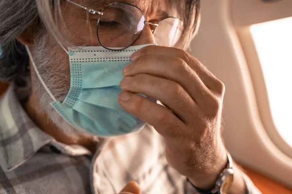 Close up view of mature man in eyeglasses wearing medical mask in private plane — Stock Photo