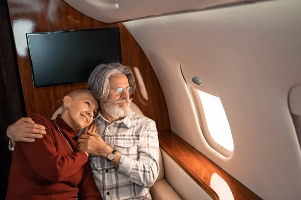 Mujer sonriente abrazando marido en avión privado - foto de stock
