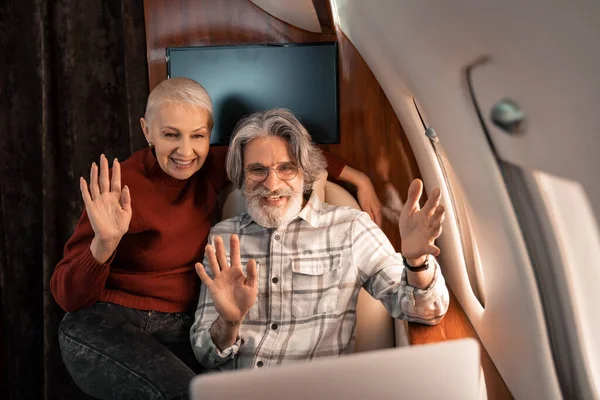 Зріла пара має відеодзвінок на розмитому ноутбуці в приватному літаку — стокове фото
