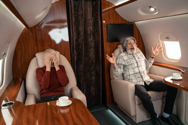 Scared man screaming near wife in cabin of airplane — Stock Photo