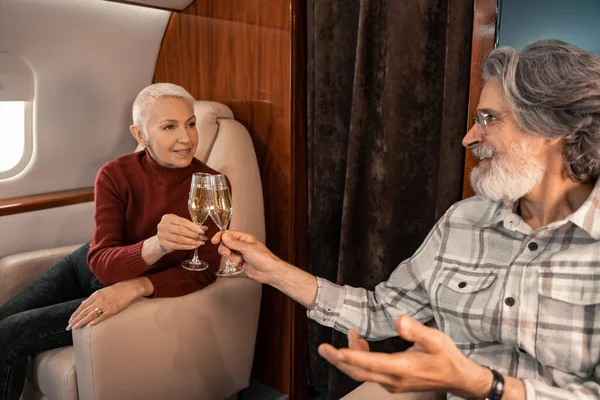 Smiling woman toasting champagne with husband in private jet — Stock Photo