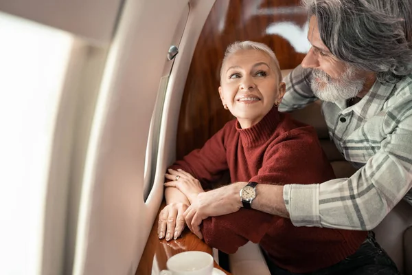 Mujer sonriente mirando al marido en jet privado - foto de stock