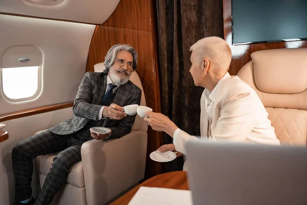 Business people clinking with coffee cups in private jet — Stock Photo