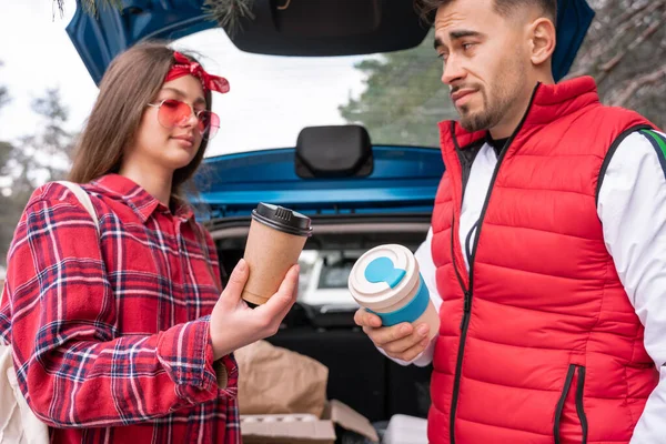 Man and woman holding reusable and paper cups near car outside — Stock Photo